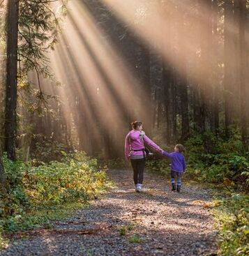 A mother and daughter walking in a small forest